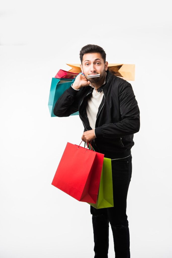 indian-asian-man-showing-his-shopping-bags-credit-debit-card-while-standing-white-backgrou (1)